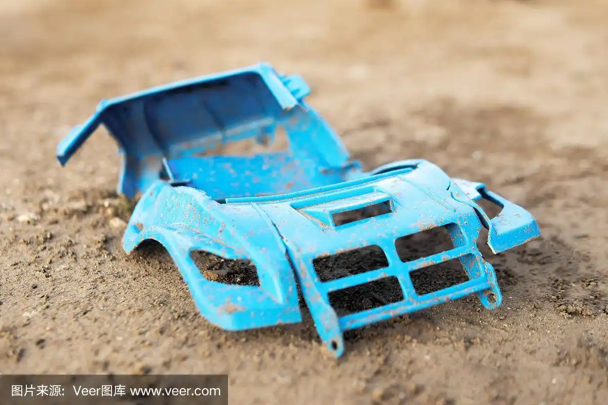 地上放着一个坏了的塑料玩具.没有轮子的破车