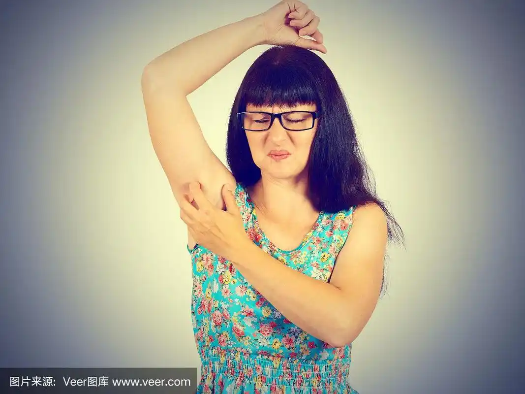 不幸的年轻女人戴着眼镜挠腋窝.