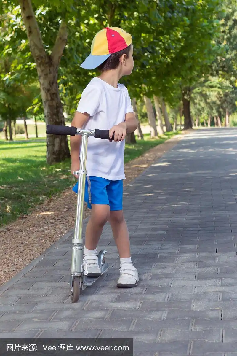 小男孩骑着滑板车在公园里玩