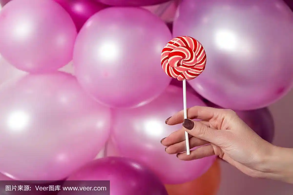 女人的手拿着一个圆形条纹糖果在背景上