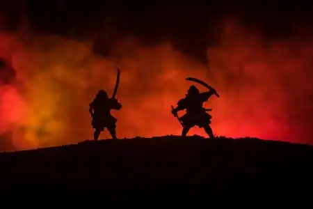 两个武士的剪影在决斗.图片与两个武士和日落的天空.选择性聚焦照片