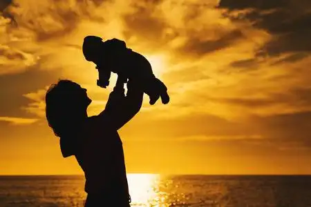 年轻的母亲在天空中抛出婴儿. 幸福家庭背景照片