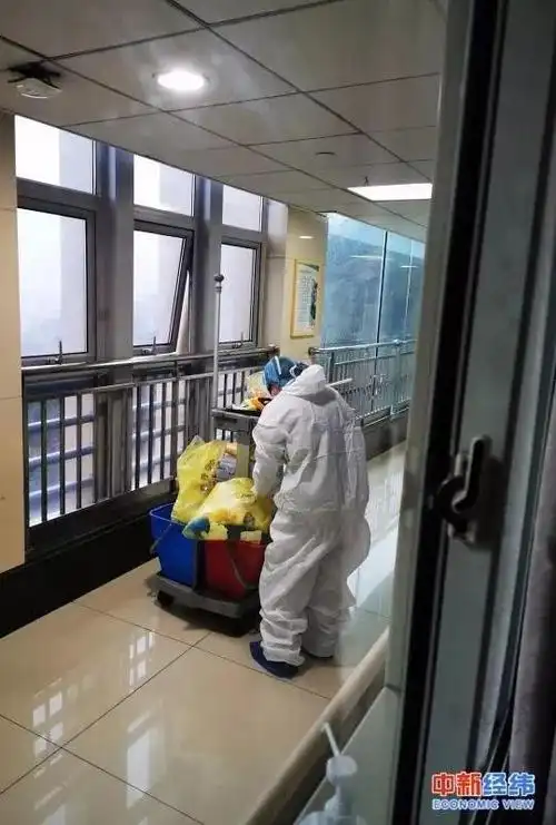病房的清洁人员正在消毒,换垃圾袋,进每个病房前都要换一次性外套.