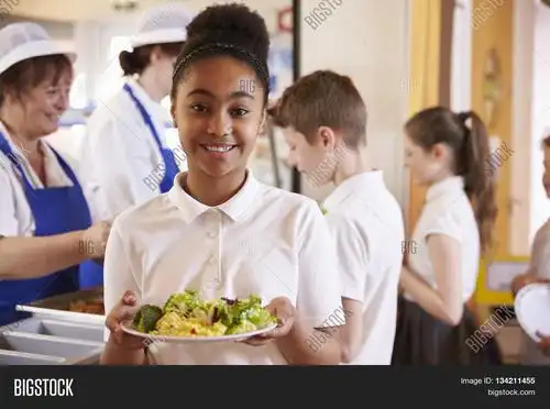 black schoolgirl holds a plate of food in a school cafeteria