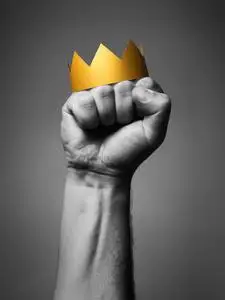 权力的概念.一个男人的拳头上的金色王冠.黑白相间照片