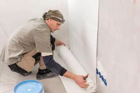 年轻人,在水泥墙上贴墙纸的工人.修理公寓.家居装修概念.
