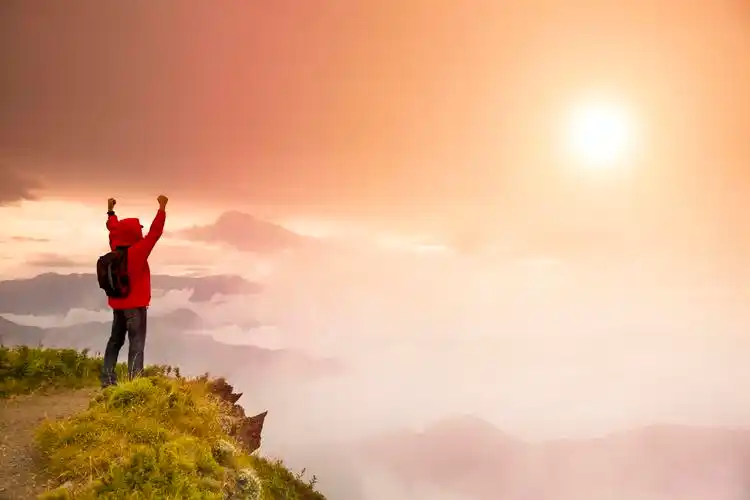 站在山顶看日出的背包的年轻人励志挑战极限突破自我
