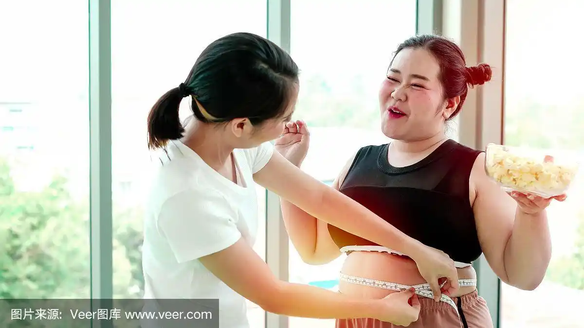 超重的年轻女子捏着她腹部的脂肪,用米量她的大码.