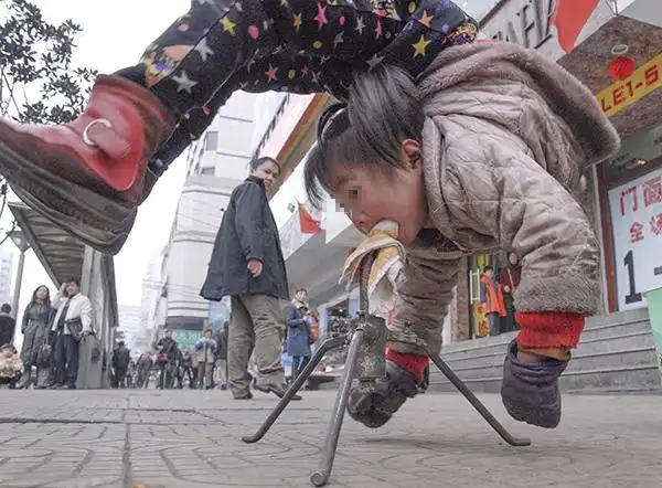 2006年2月26日,贵阳街头,一个女孩在街头卖艺. 视觉中国 资料图