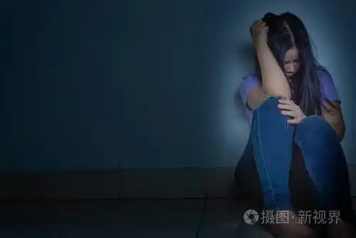 一个悲伤的女人独自坐在黑暗的房间里哭泣dep公司