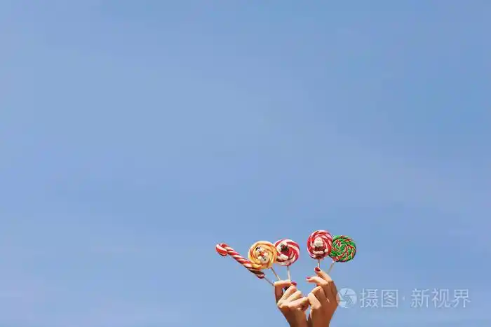 蓝色天空背景下妇女手拿彩色圣诞糖果文本空间圣诞节概念