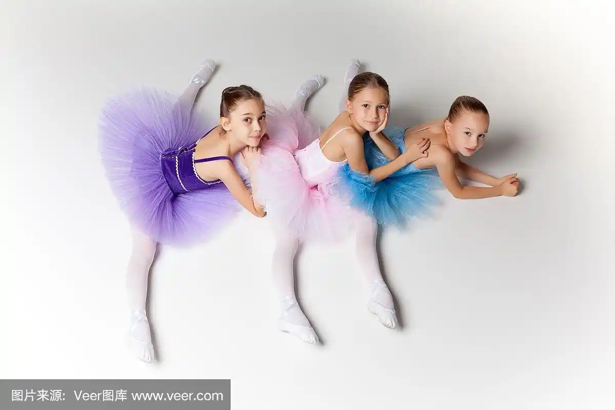 三个芭蕾舞小女孩穿着芭蕾舞裙坐在一起摆姿势
