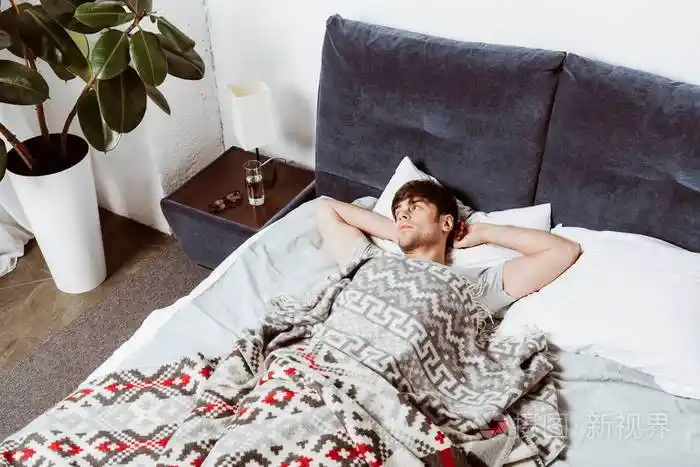 高面手的角度看, 英俊的男人躺在床上, 在早上的时间在家里