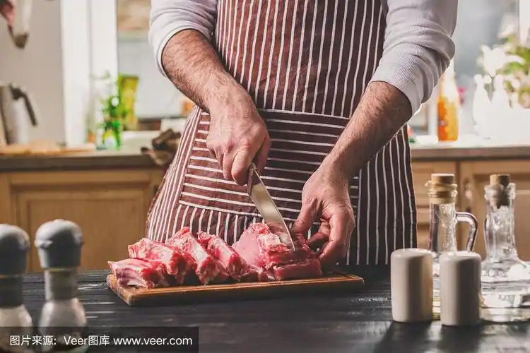 男人在家庭厨房的木板上切新鲜的牛肉块