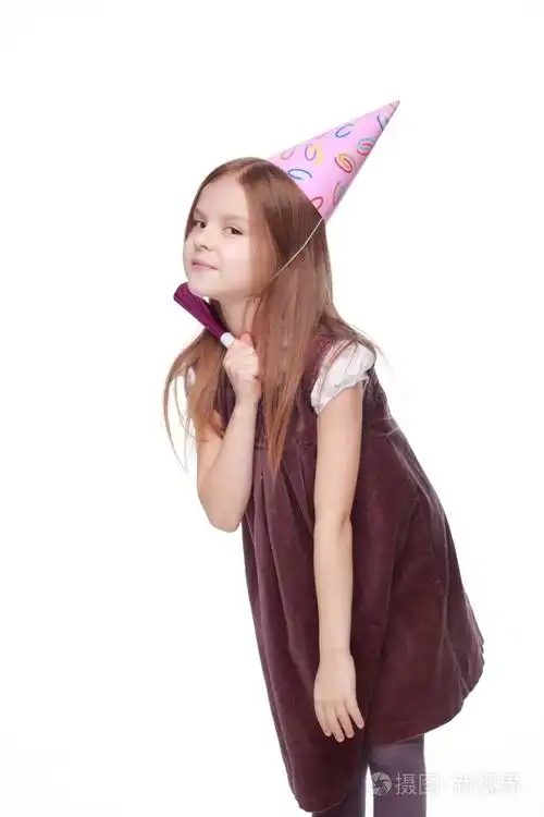 孩子女孩在生日聚会上的白色背景图像上的横笛和假日帽子可爱穿裙子的