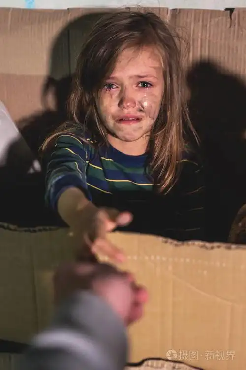 哭泣无家可归的孩子女孩坐在纸板箱和蔓延的手臂