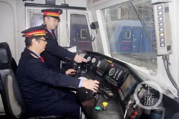 喻伟站在旁边指导年轻的司机掌握火车驾驶.