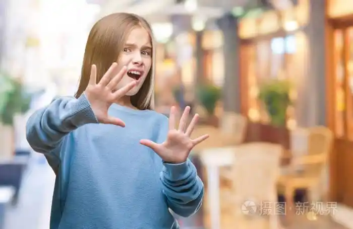 年轻美丽的女孩穿着冬天的毛衣在孤立的背景害怕和恐惧的表情停止手势