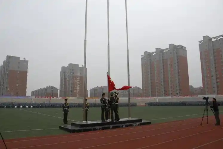 国旗护卫队步入旗台,鲜红的五星红旗冉冉升起在田径场上空,开学典礼暨