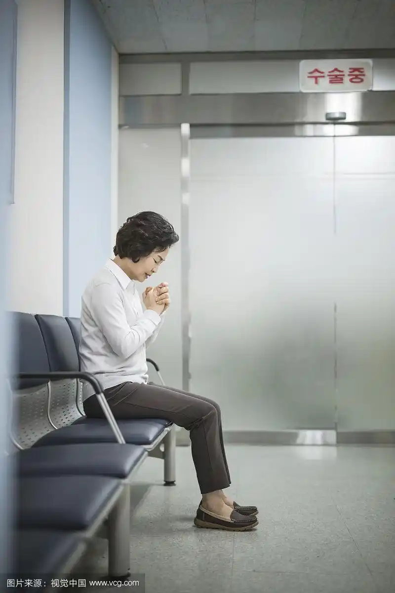 老妇人在手术室前祈祷