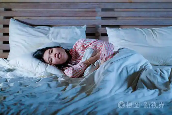 年轻美丽疲倦多病的亚裔日本妇女躺在家里病倒在床上在医疗保健方面患