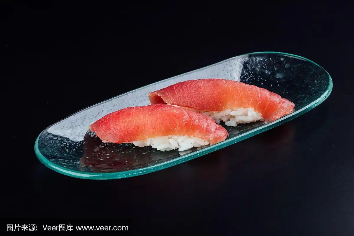 盘子里有两条新鲜的黑鲔鱼,在黑色的背景上