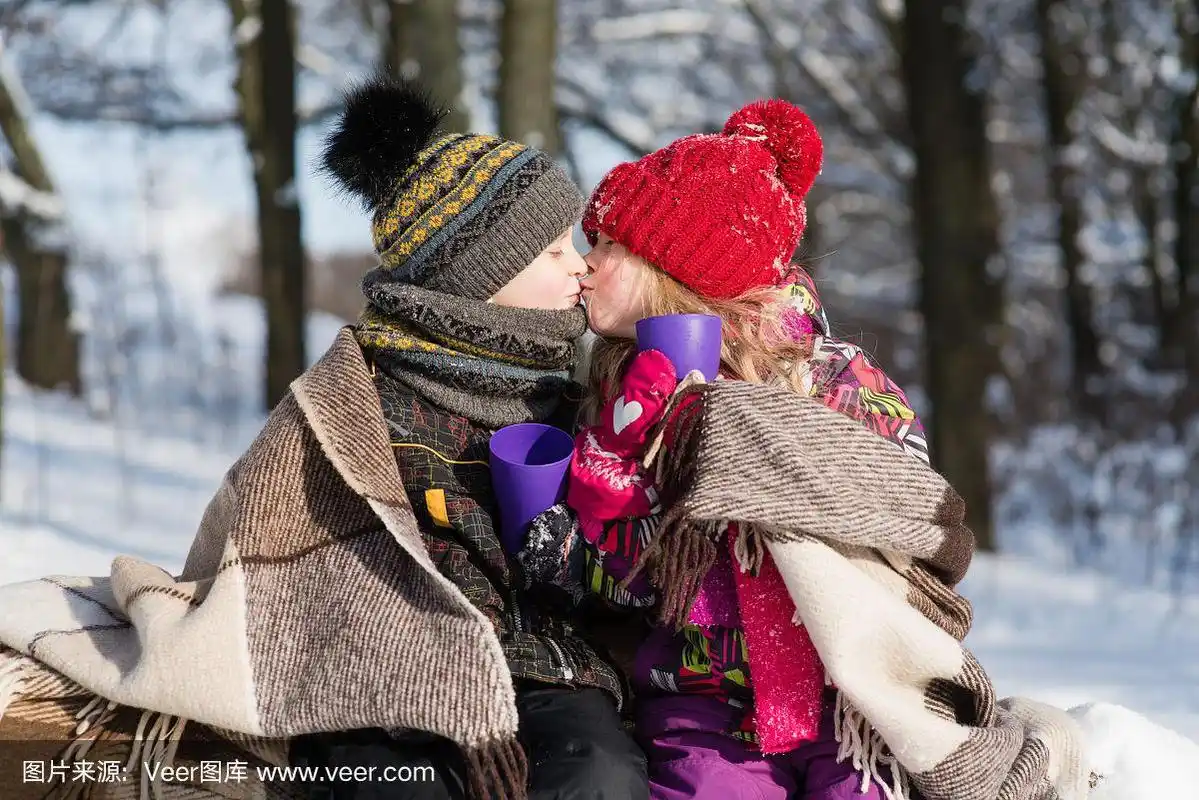 小女孩带着礼物在户外亲吻小男孩