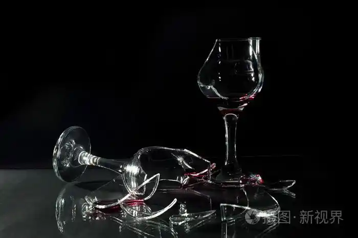 洒上黑孤立的玻璃桌上的碎的玻璃杯子里的红酒