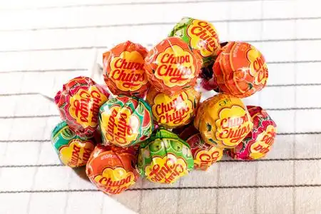 一堆丘帕杯棒棒糖糖果近距离观看白色织物桌布从高角度.照片