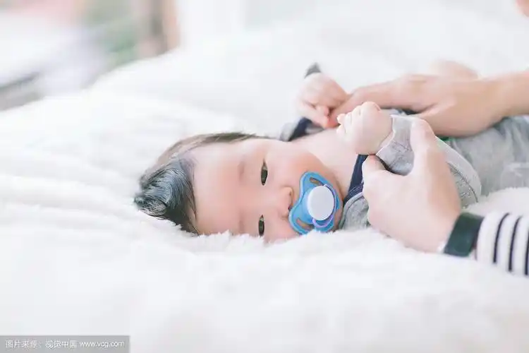 可爱的婴儿吸着奶嘴,睡在柔软的白色地毯上.