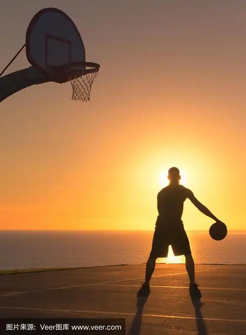在日落时运球的篮球运动员.轮廓