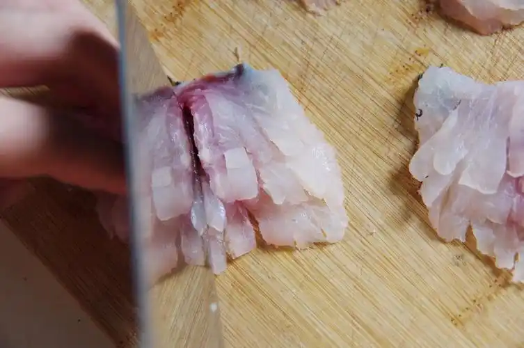 8. 在每组鱼片上纵向下刀,将鱼片切成条状,鱼肉部分分开,鱼皮处相连.