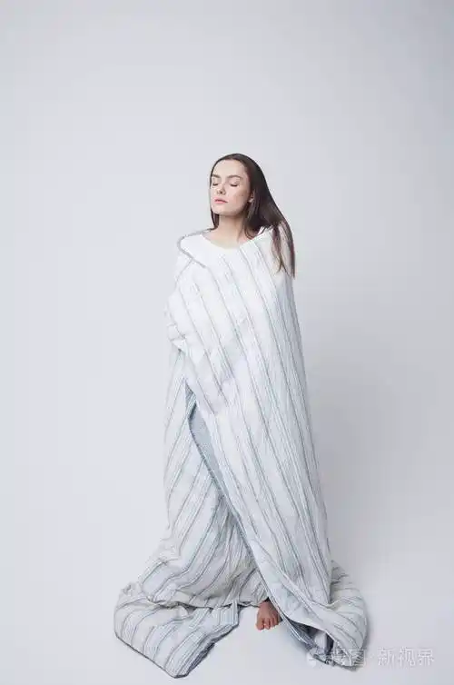 健康的睡眠和困倦美丽的年轻女子裹着毯子站着