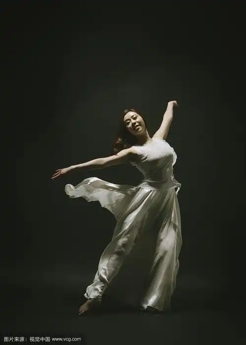 摄影的女人与白色的衣服跳舞赤脚在黑色的背景