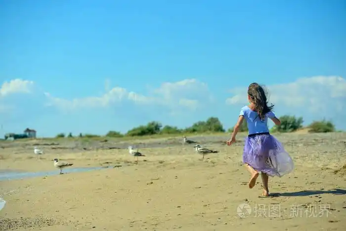 快乐的小女孩在阳光明媚的日子里, 在沙滩上玩耍, 沿着海滩奔跑, 在