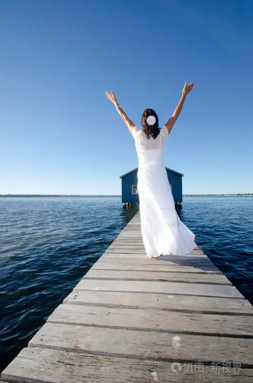 快乐的女人白色礼服在海上浮桥上