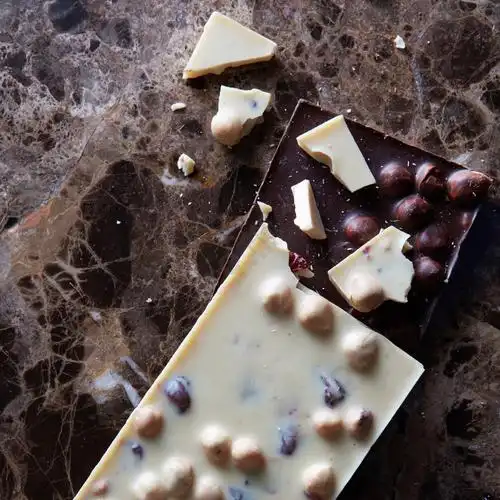 黑色大理石背景上孤立的黑色和白色巧克力瓷砖黑巧克力和白巧克力