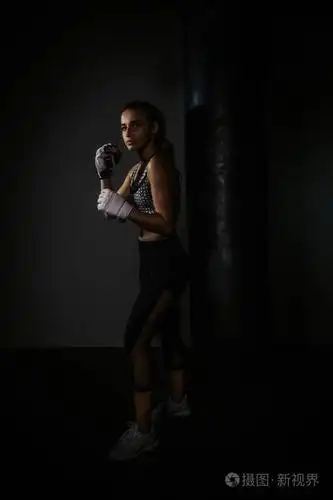 年轻漂亮的拳击手在黑暗的健身房里