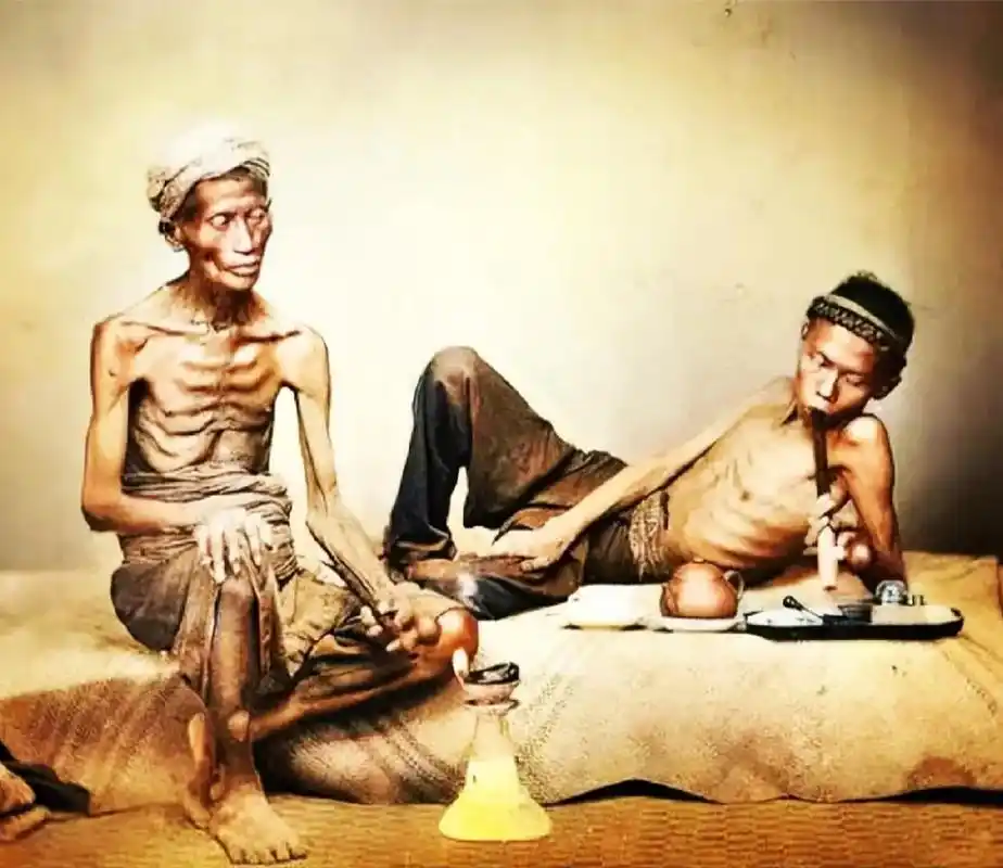 图中的两名男子正在吸食鸦片,身体两侧的肋骨已清晰可见,骨瘦如柴.