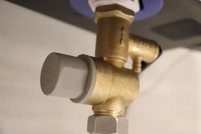 严格来说是热水器进水管的下面,有一个三角形的金属阀门