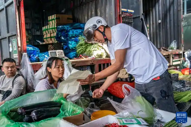 69695月14日,罗瑞(右)在玉溪市的一家菜市场买菜.