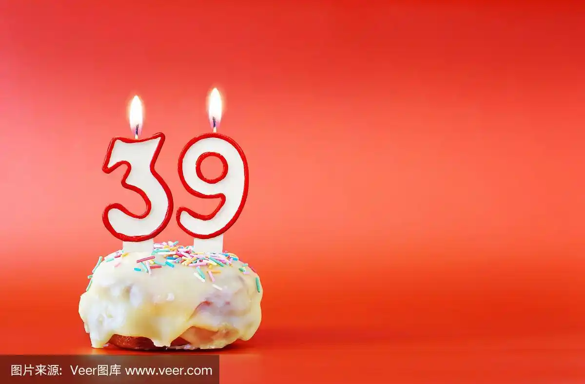 纸杯蛋糕,上面有燃烧着的白色蜡烛,数字39.鲜艳的红色背景与复制空间