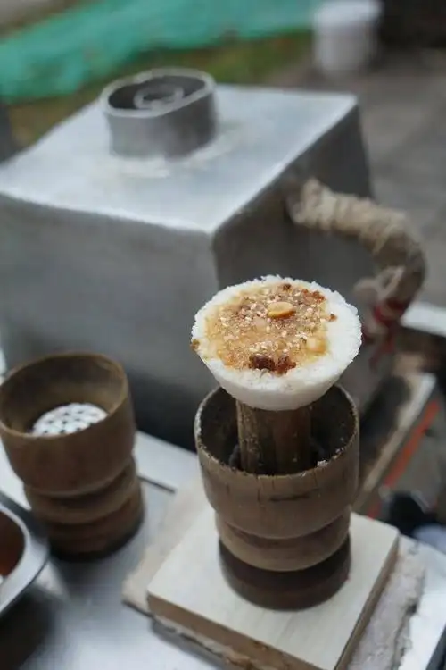 蒸蒸糕的做法很简单,把糯米粉,糖,花生芝麻放进一个拳头大的木质漏斗