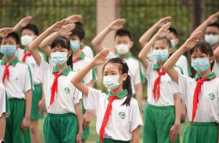 其他学生在各自的课室里师生同样佩戴着口罩,面向课室里高挂的国旗