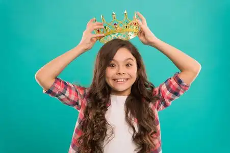 女孩可爱的婴儿戴皇冠, 而站蓝色背景.成为公主的概念.