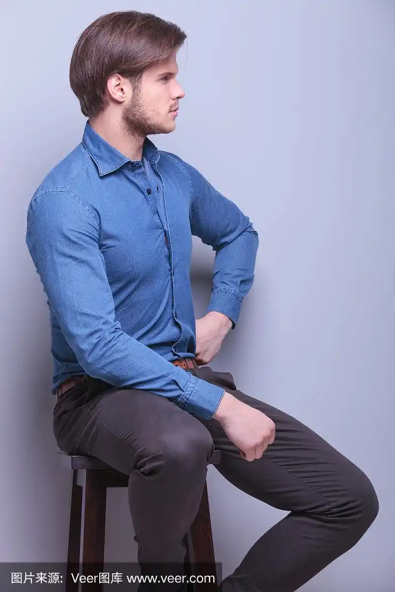 一个年轻的时尚男子坐着的侧视图