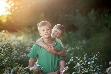 两个人站立拥抱两个男孩兄弟朋友在夏日阳光明媚的日子里拥抱.