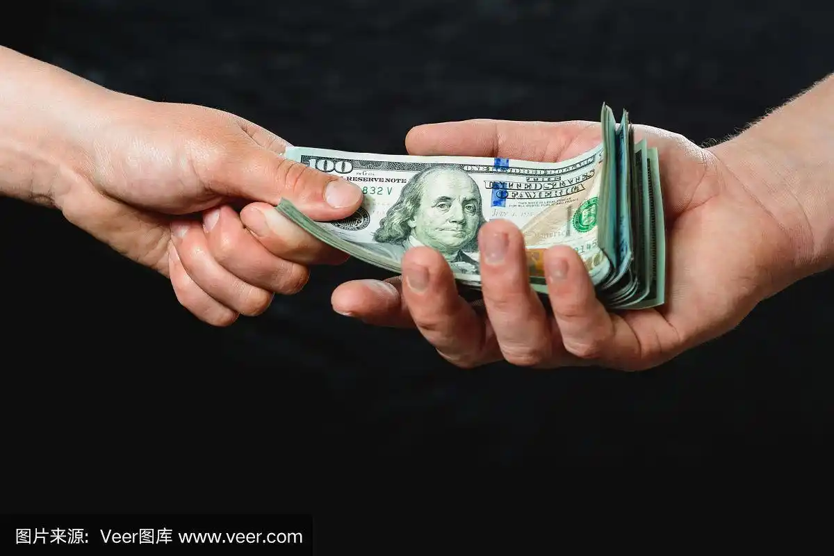 一个商人的手拿着钱在一个黑色背景的特写.