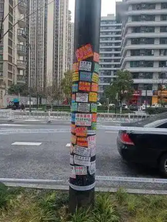 电线杆,公告栏,公交车站牌,路边电箱上,"像被盖章一样"贴满了小广告