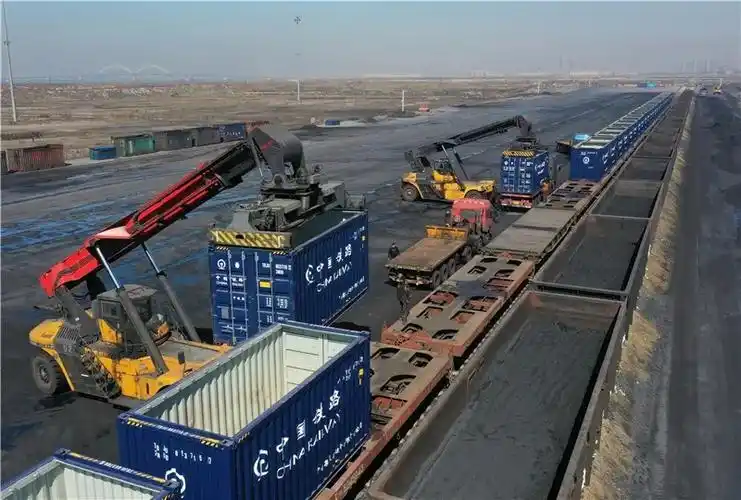 工人操作机械设备往列车上吊装卸完货物的集装箱